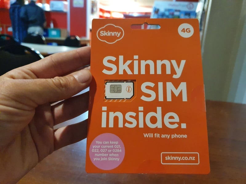 man holding the packet of a skinny sim card