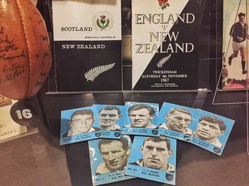 a photo showing seven collectable cards and two rugby books about New Zealand and England games
