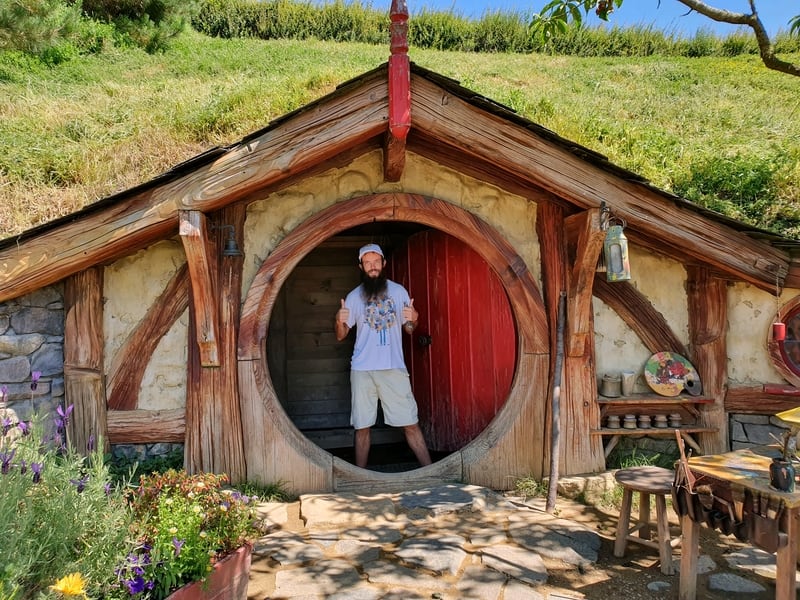picture of jub standing in a hobbit hole with a red door