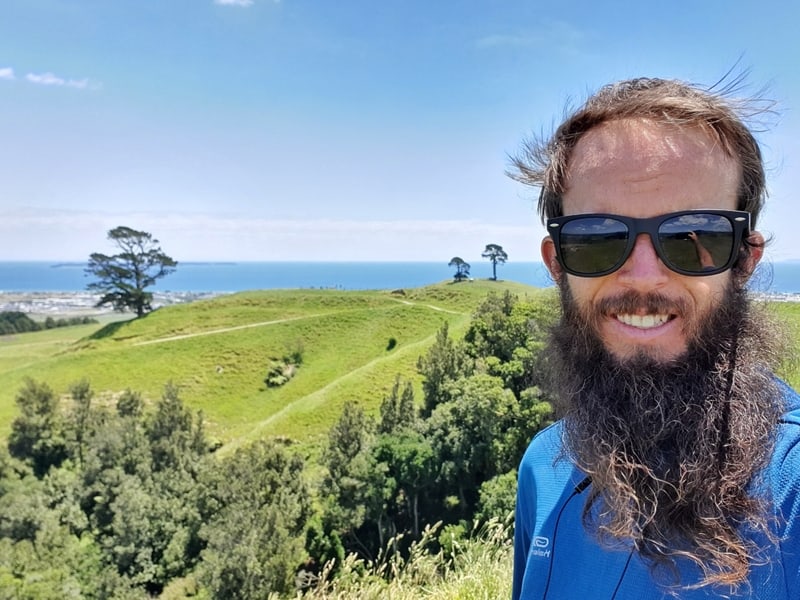 a selfie from the summit of Papamoa hills, with trees, grass, and ocean in the background