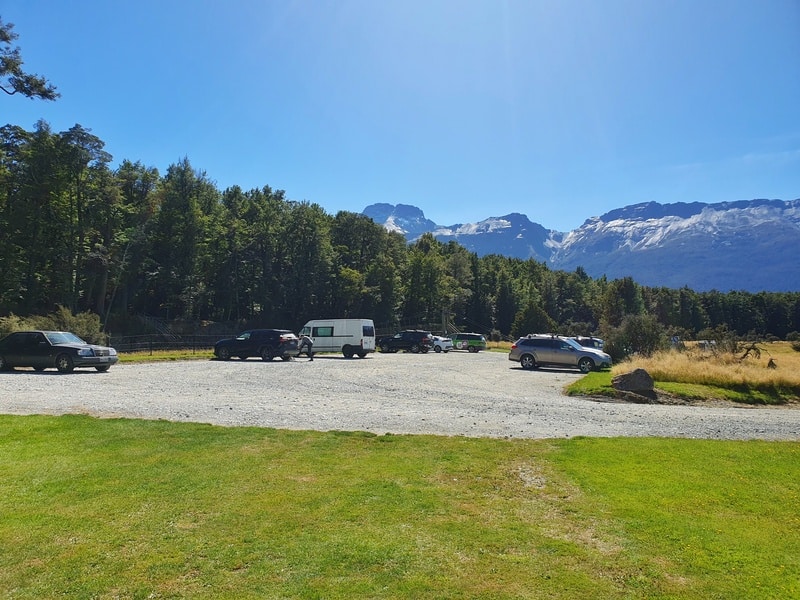 cars in a gravel carpark with mountains in the bacground