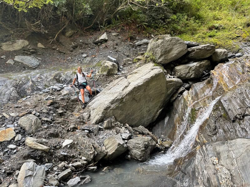 Otago Cameron Hut surrounded by rocks and a small stream in a scenic wilderness area.